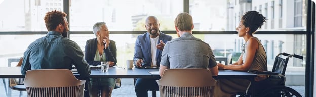 A collective of people that are sitting in a conference room desk